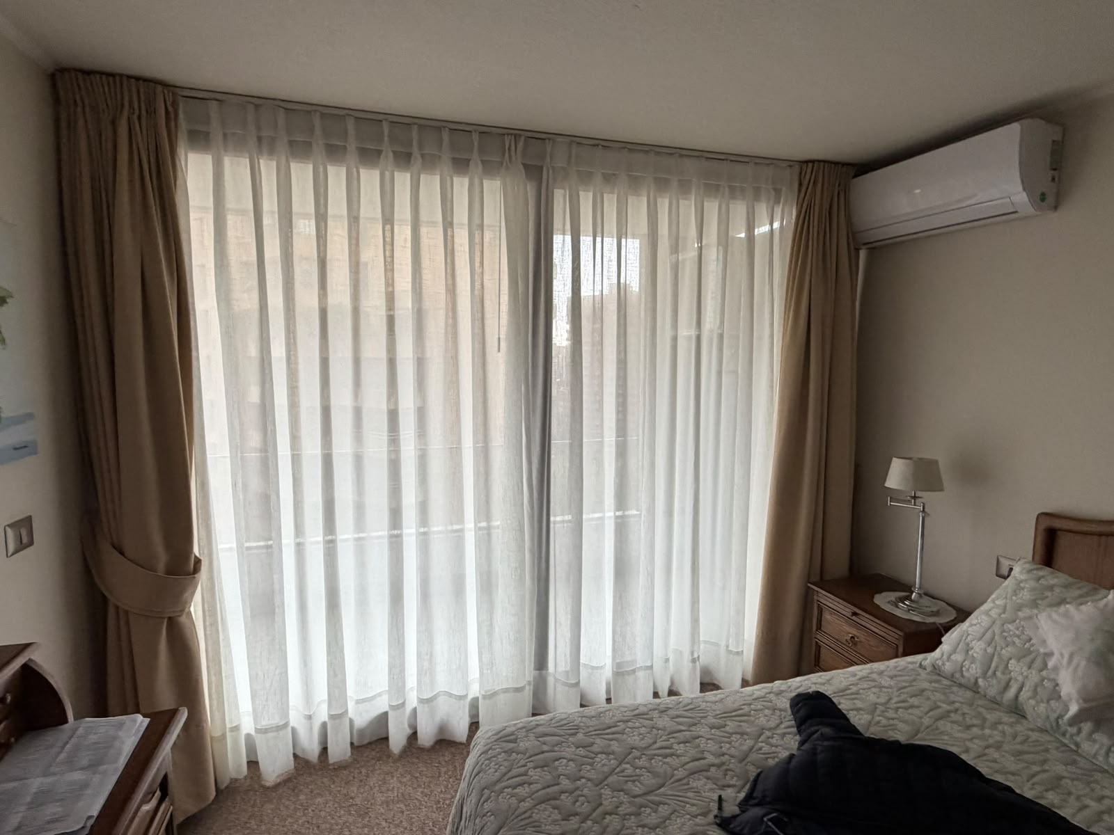 Dormitorio con visillo blanco liviano combinado con cortina beige para el verano